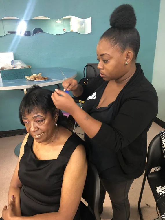 A stylist working on a client's hair at a salon station